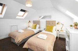 two beds in a room with white walls and windows at Ambler Thorn Lodge in Queensbury