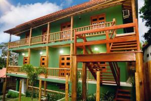 una casa verde con una gran terraza. en Encanto do mar residencial en Caraíva
