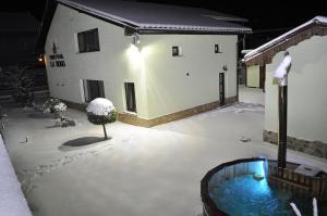 a snow covered yard with a tub in front of a building at Pensiunea La Rogo in Vulcan