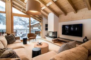 a living room with a couch and a tv at Berghof Penthouse in Saas-Fee