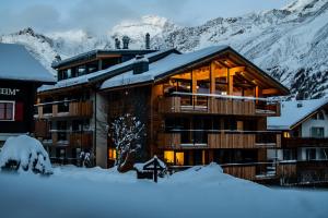 a lodge in the snow with mountains in the background at Berghof Penthouse in Saas-Fee