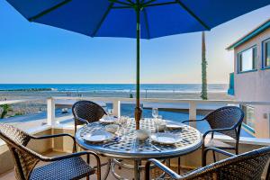 een tafel met stoelen en een parasol op het strand bij Seascape Homes in Newport Beach