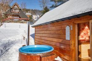 a hot tub outside of a building in the snow at Witkówka New Folk Luxury - Sauna & SPA x in Kościelisko