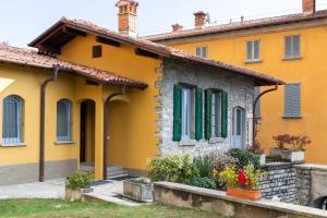 a yellow house with green shutters at La Casetta in Tremezzo