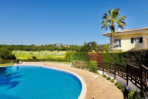 una piscina frente a una casa con palmeras en Villa Formosa Golf en Quinta do Lago