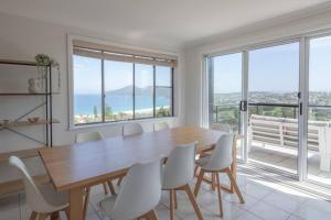 a dining room with a wooden table and white chairs at Dreamtime Beach Retreat in Forster
