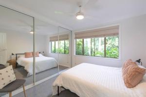 a white bedroom with two beds and a window at Dreamtime Beach Retreat in Forster