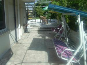 a porch with a swing and chairs on a house at Family Hotel George in Svilengrad