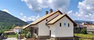 a white house with a roof with mountains in the background at Casa Cotefablo. Aloj Sorrosal (Gavin, Biescas) in Gavín
