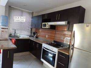 uma cozinha com armários pretos e um frigorífico branco em Bonita Casa en Condominio con Alberca y Acceso al Lago em Tequesquitengo