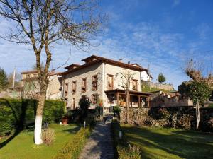 a large house with a tree in front of it at La Casona del Jou in Ortiguero