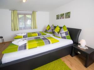 ein Schlafzimmer mit einem Bett mit gelben und grünen Kissen in der Unterkunft Appartement Bergmeister in Rauris