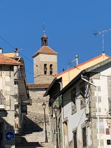 un edificio con una torre de reloj y una iglesia en El balcón de Araceli, en Cercedilla