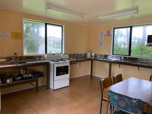 cocina con fogones, mesa y ventanas en Greymouth Kiwi Holiday Park & Motels, en Greymouth