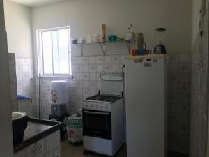 Mar Azul Condomínio في أراكاجو: مطبخ مع موقد وثلاجة بيضاء