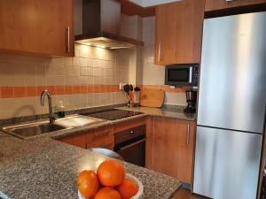 a kitchen with a white refrigerator and a bowl of oranges at Acogedor apartamento en Boiro in Boiro