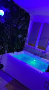 bañera de hidromasaje en una habitación con luces moradas en L'extasia appartement,spa jacuzzi Grenoble en Grenoble
