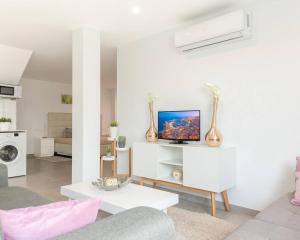 a living room with a couch and a tv on a wall at Lily’s Casa in Benijófar