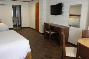 a hotel room with a desk and a bed and a tv at Hotel Adriana in Hidalgo del Parral