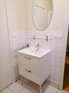 une salle de bains blanche avec un lavabo et un miroir dans l'établissement EK Studio Appartement, à Saint Etienne