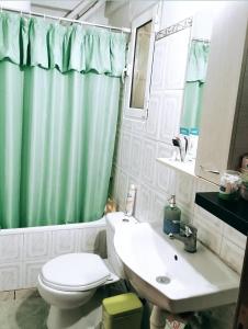 a bathroom with a green shower curtain and a toilet and sink at •Budget travellers •Great location in Athens