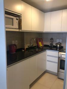 cocina con armarios blancos y microondas en Apartamento Apolo, Depto 201 sobre Gorlero, en Punta del Este