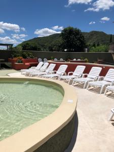 a group of white chairs sitting next to a swimming pool at Los Naranjos Apart Hotel in Villa Carlos Paz