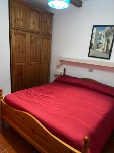 a bedroom with a red bed with a wooden cabinet at IL GECO DI MONTAGNA in Castel di Sangro