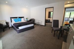 1 dormitorio con 1 cama, escritorio y sillas en Palm City Motor Inn, en Napier