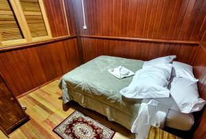 a small bed in a room with wooden walls at Recanto Baú - Chalé in Bom Jardim da Serra