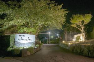 una strada di notte con un cartello che dice "Incontra sufi" di Hotel JuJu a Kurume