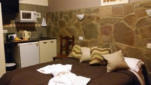 una cama en una habitación con una pared de piedra en Kawo Apart Hotel, en Puerto Santa Cruz