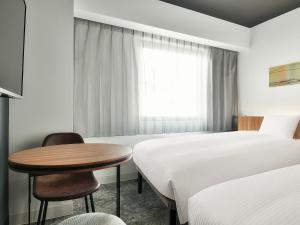 大阪市にあるベッセルインなんばのテーブルとベッド2台が備わるホテルルームです。