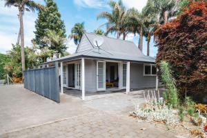 ein weißes Haus mit einem Zaun und Palmen in der Unterkunft Te Puna Cottage Gardens B&B in Tauranga