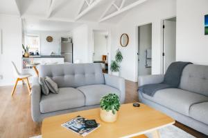 ein Wohnzimmer mit 2 Sofas und einem Tisch in der Unterkunft Te Puna Cottage Gardens B&B in Tauranga