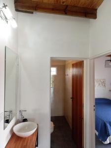 Un baño con lavabo, inodoro y una cama. en Complejo Joansa, en Villa Santa Cruz del Lago