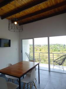 Un comedor con mesa y sillas y una gran ventana. en Complejo Joansa, en Villa Santa Cruz del Lago