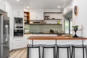 a kitchen with white cabinets and a counter with bar stools at Coorabell Estate in Coorabell Creek