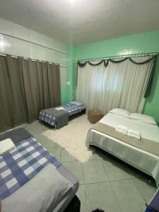 twee bedden in een kamer met groene muren bij Kitnet Praia do Trapiche in Penha