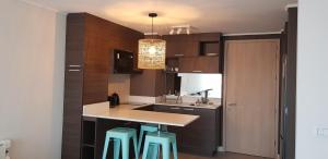 una cocina con armarios marrones y taburetes azules en Departamento nuevo con la mejor ubicación, en Viña del Mar