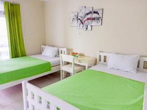 Homestay Sakinah Belitung RedPartner في Tanjungbinga: سريرين في غرفة مع شراشف خضراء