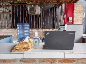 Homestay Sakinah Belitung RedPartner في Tanjungbinga: جهاز كمبيوتر محمول على طاولة مع حقيبة وزجاجة من الماء
