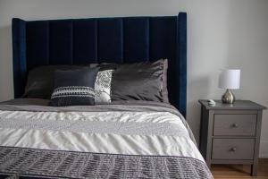 a bed with a blue headboard next to a night stand at Downtown High-rise Condo- CN Tower View in Toronto