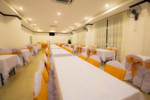 a banquet hall with white tables and orange chairs at Douangchan Plaza Hotel in Vientiane