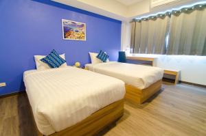 sypialnia z 2 łóżkami i niebieską ścianą w obiekcie Bleu Marine Sattahip Hotel w mieście Ban Nong Sa