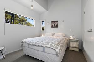 een witte slaapkamer met een bed en een raam bij Boulevard Beauty - Langs Beach Holiday Home in Langs Beach