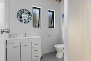 Baño blanco con lavabo y aseo en Boulevard Beauty - Langs Beach Holiday Home, en Langs Beach