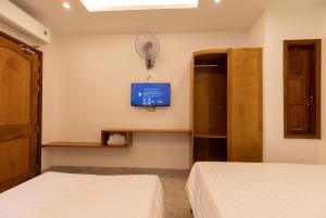 a bedroom with two beds and a tv on the wall at 26 Topaz Hotel in Vung Tau
