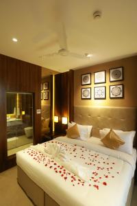 a bedroom with a bed with red rose petals on it at Magnet Hotel in Kannur
