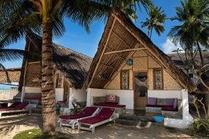 a house on the beach with palm trees at Nur Beach Hotel in Jambiani